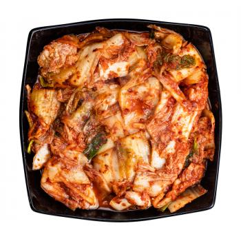 top view of korean appetizer kimchi from napa cabbage in black bowl isolated on white background