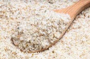 above view of wooden spoon with psyllium husk close up on pile of sugar