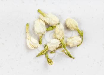 several dried jasmine flowers close up on gray ceramic plate
