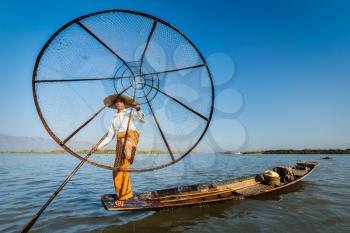 Myanmar travel attraction landmark - Traditional Burmese fisherman with fishing net at Inle lake in Myanmar famous for their distinctive one legged rowing style