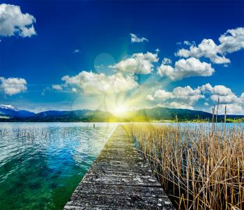 Pier in the lake in countryside on sunset with sunrays, Bavaria, Germany