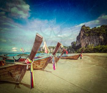 Vintage retro hipster style travel image of Long tail boats on tropical beach (Railay beach) in Thailand with grunge texture overlaid