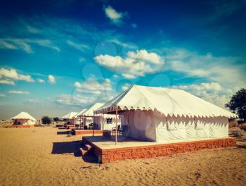 Vintage retro hipster style travel image of luxury tents in desert. Jaisalmer, Rajasthan, India