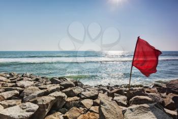 Danger - Red flag on rocky beach forbidding to swim