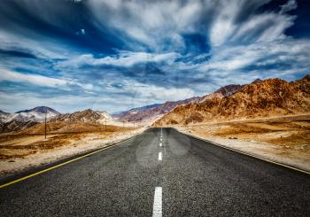 Travel forward concept background - road in Himalayas mountains and dramatic clouds. Ladakh, Jammu and Kashmir, India