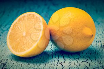 Vintage retro effect filtered hipster style image of lemon and cut half slice on blue wooden background