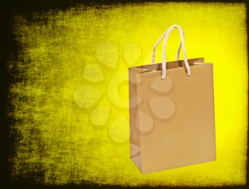 Empty golden shopping bag on a yellow grungy background.