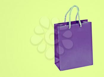 Empty purple shopping bag isolated on green background.
