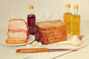 Sliced bread,bacon and olive oil on white kitchen table.
