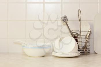 White kitchenware on kitchen table and ceramic tile background.