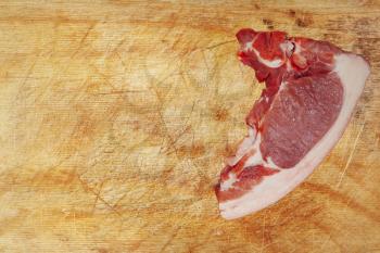 Raw pork meat on wooden cutting board taken closeup and empty space.Top view.