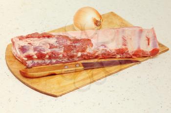 Raw pork ribs,knife and onion on kitchen table taken closeup.