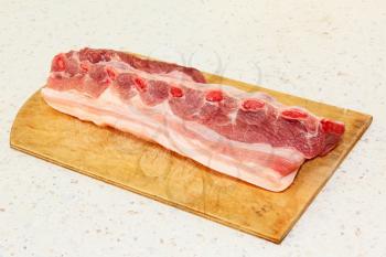 Raw pork ribs on wooden cutting board taken closeup.