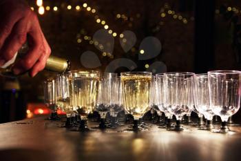 Waiter pour wine in the glass on holiday reception table in night-time lighting.