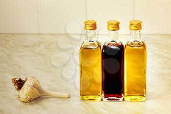 Three olive oil bottles and garlic on kitchen table.Toned image.