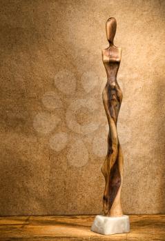 Stylized woman wooden figurine on grunge background.