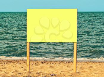 Yellow blank billboard on sandy beach against of sea surf.Just add your text.