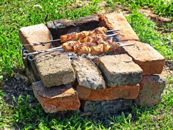Appetizing kebab is preparing on barbecue in brick rustic brazier.