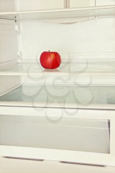 Single red apple in domestic refrigerator. Toned image.