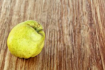 Appetizing ripe quince on grunge wooden background taken closeup.
