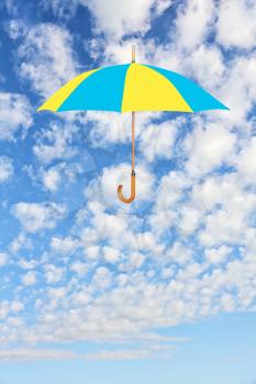 Wind of change concept.Umbrella in Ukrainian flag colors flies in sky against of white clouds.Mary Poppins Umbrella.