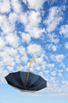 Overturn Black Umbrella flies in sky on white clouds background.Mary Poppins Umbrella.