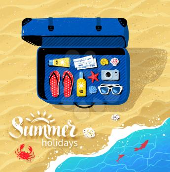 Top view of travel suitcase with summer accessories on beach sand and sea surf background.
