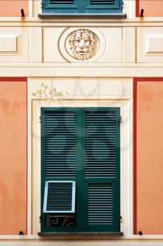 green wood venetian blind a  pink yellow red  wall and a head of lion  in the centre chiavari italy