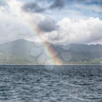 from a boat the rainbow from  ocean and island in background