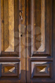 abstract cross   brass brown knocker in a   closed wood door   varese italy sumirago sunny day