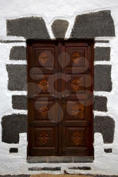 brass brown knocker in a brown closed wood  door and white wall lanzarote abstract  spain canarias
