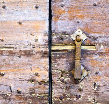 abstract   rusty brass brown knocker in a  door curch  closed wood lombardy italy  varese azzate