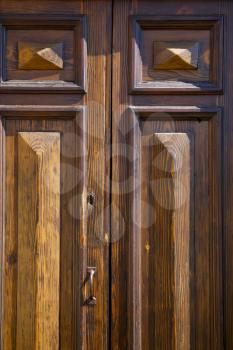 abstract cross   brass brown knocker in a   closed wood door   varese italy sumirago sunny day