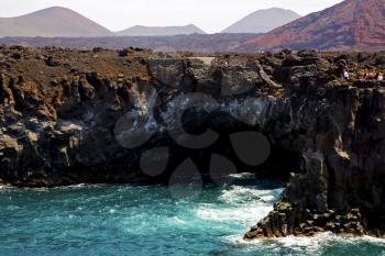 people   coastline stone volcanic spain  water  in lanzarote  sky cloud beach  and summer 
