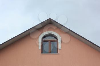 Detail of the roof of a building with a window on the background of blue sky