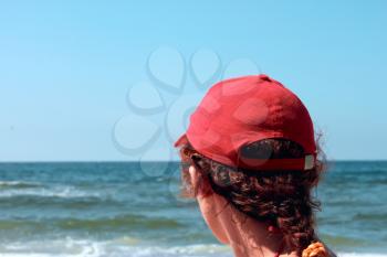 A woman in a red cap looks marine vistas