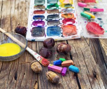 set of different paint colors and  brush for painting on wooden background in the autumn style