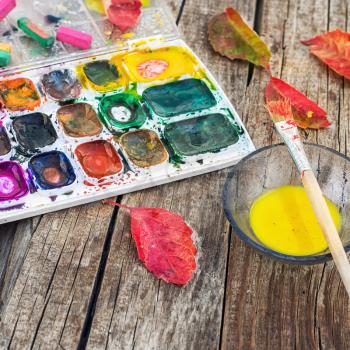 set of different paint colors and  brush for painting on wooden background in the autumn style