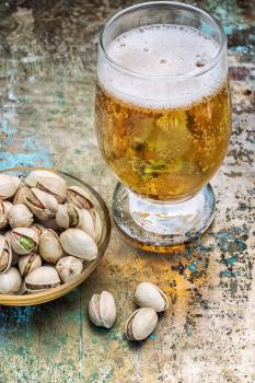 one glass glass of light beer with scattered on the table pistachios.Photo tinted