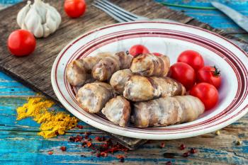 Turkey sausages roasted on round plate on wooden surface with tomatoes and spices.The image is tinted.Selective focus