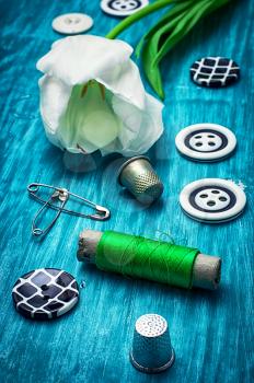 white tulip and buttons for clothing on light blue wooden background.the image is tinted in vintage style