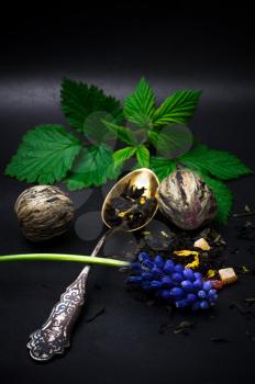 dry leaves of the tea infuser and accessories on black background