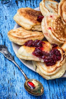 pancakes drizzled with jam on blue wooden board.