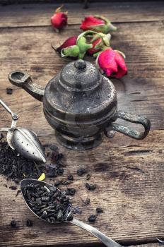 Dried tea leaves in spoons on stylish background of the teapot.