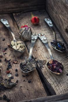 Vintage spoons in wooden box with spilling tea of different types