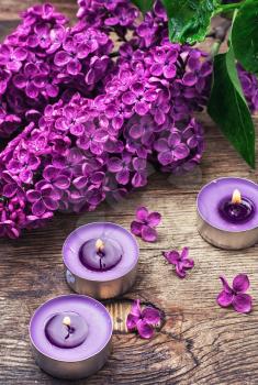 Broken fragrant branch with lilac flowers and burning candles.