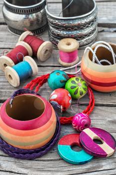 Stylish beads and spools of thread on wooden background