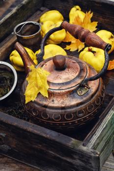 Obsolete wooden box with a stylish copper kettle and fruit quince