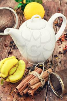 White glass teapot and  quince tea on wooden background