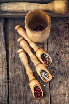 Three kinds of pepper in wooden spoons on vintage background